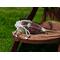 Irish Twins Potpourri sachet in red, green, and brown tones on a rustic wooden chair, placed outdoors with a vibrant green grass background.